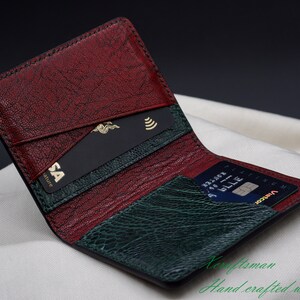 May include: Open leather wallet with a textured burgundy and green interior. The wallet contains a black credit card with a gold Visa logo and a blue credit card. The words "Craftsman" and "Hand crafted with passion" are visible.