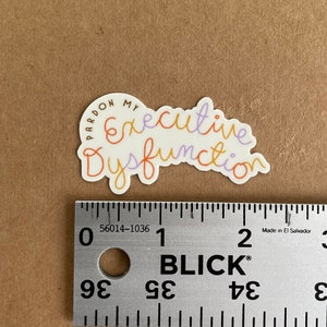 May include: A white sticker with the text "Pardon My Executive Dysfunction" written in a colorful, handwritten style. The text is in a curved shape, with the words "Pardon My" in a smaller font size and a brown color. The words "Executive Dysfunction" are in a larger font size and are written in a rainbow of colors, including purple, orange, and yellow.