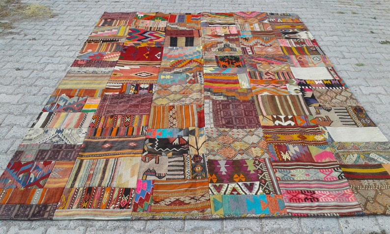 May include: A large, colorful patchwork rug made from various pieces of fabric. The rug features a variety of geometric patterns and colors, including red, blue, green, yellow, and orange.