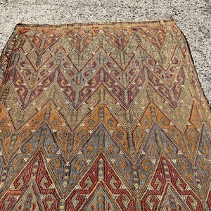 Pode incluir: Um tapete vintage com um padr&atilde;o geom&eacute;trico em tons de marrom, vermelho e cinza. O tapete tem um design tradicional com detalhes intrincados.