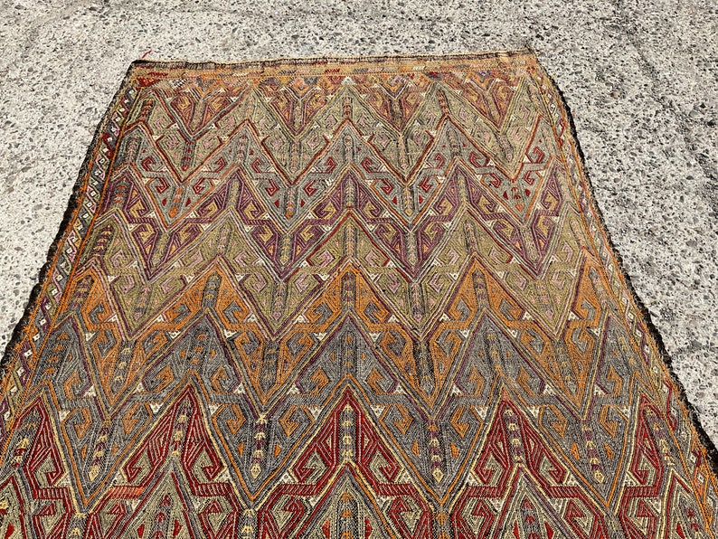 Pode incluir: Um tapete vintage com um padr&atilde;o geom&eacute;trico em tons de marrom, vermelho e cinza. O tapete tem um design tradicional com detalhes intrincados.
