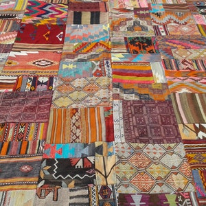 May include: A large patchwork rug made from various colorful fabrics with geometric patterns. The rug is made up of many different squares and rectangles, each with a unique design. The colors are vibrant and bold, and the overall effect is one of intricate detail and craftsmanship.