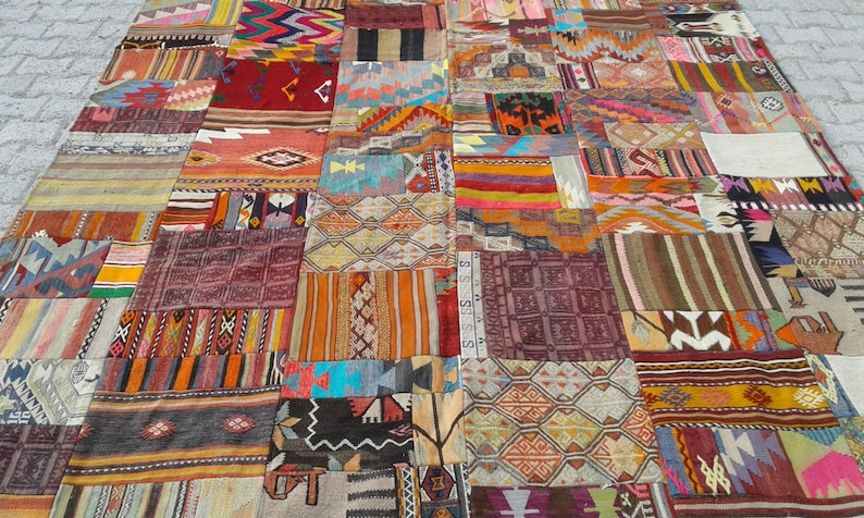 May include: A large patchwork rug made from various colorful fabrics with geometric patterns. The rug is made up of many different squares and rectangles, each with a unique design. The colors are vibrant and bold, and the overall effect is one of intricate detail and craftsmanship.