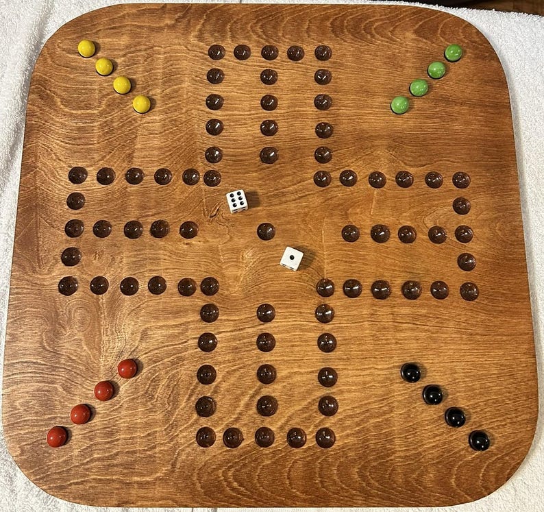 Puede incluir: Un tablero de juego de madera con una mancha marr&oacute;n. El tablero tiene una cuadr&iacute;cula de agujeros con canicas en ellos. Tambi&eacute;n hay dados y otras piezas de juego en el tablero.