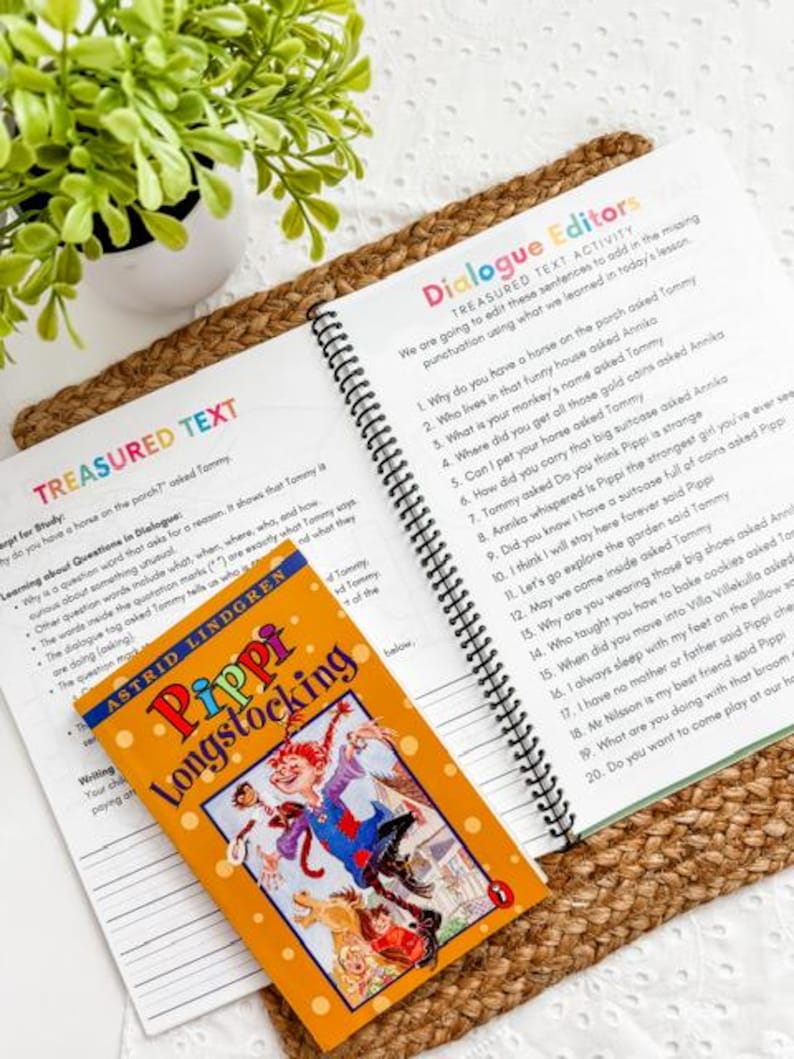 May include: An open book with spiral binding next to a children's book titled "Pippi Longstocking" by Astrid Lindgren. The book cover features a cartoon illustration of a girl. The text "Dialogue Editors" is visible.