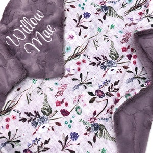 Puede incluir: Una suave manta de felpa morada para beb&eacute; con estampado floral y el nombre "Willow Mae" bordado en la esquina.