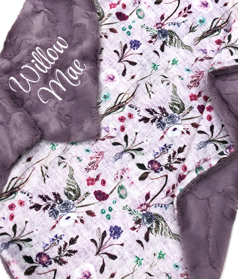 Puede incluir: Una suave manta de felpa morada para beb&eacute; con estampado floral y el nombre "Willow Mae" bordado en la esquina.