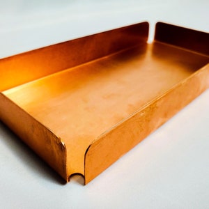 May include: A rectangular copper tray with slightly raised edges. The tray is empty and has a smooth, polished surface.