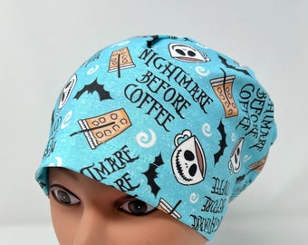 May include: A light blue scrub cap featuring a repeating pattern of coffee cups, bats, and the phrase "Nightmare Before Coffee" in black and white. The cap is designed to fit snugly on the head.