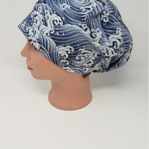 May include: A blue and white patterned scrub cap. The cap features a repeating design of stylized ocean waves. The cap is made of a soft fabric and is designed to cover the hair.