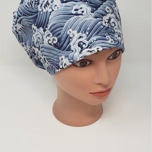 May include: A blue and white patterned scrub cap featuring a wave design. The cap is made of fabric and is designed to cover the head. The wave pattern is in shades of blue and white.