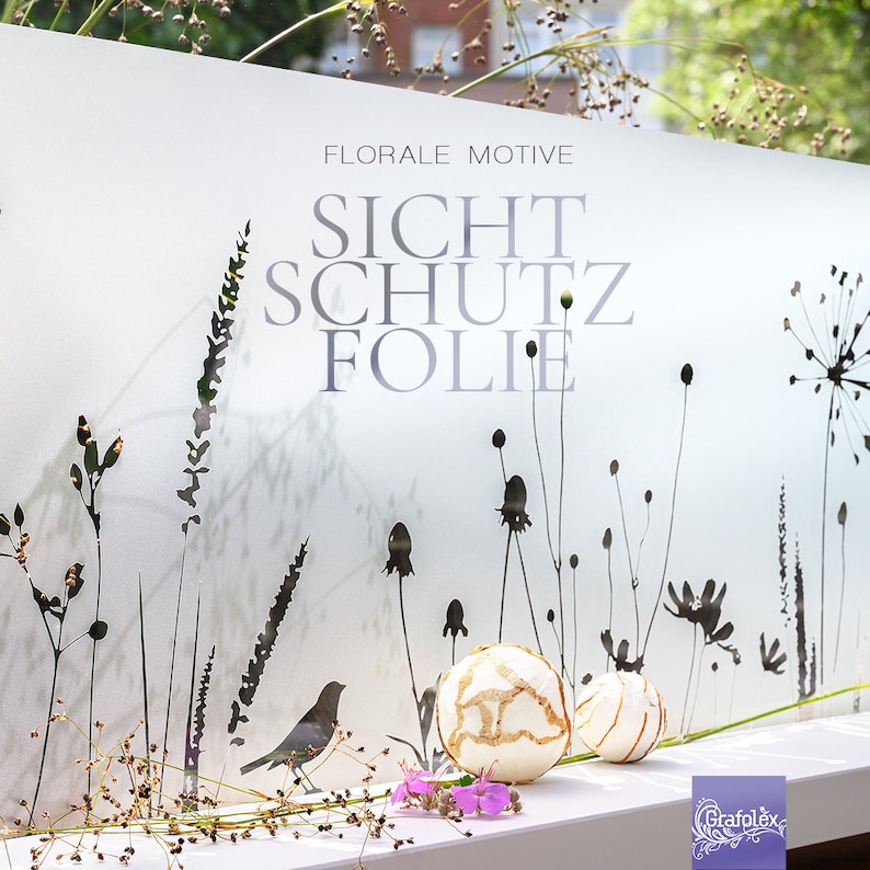 May include: A white frosted window film with a floral design and the text "FLORALE MOTIVE SICHTSCHUTZ FOLIE". The film is designed to provide privacy and block unwanted views. Two white decorative balls are in the foreground.