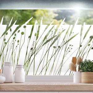 Könnte beinhalten: Eine Milchglasfolie mit einem Silhouettenmuster aus hohem Gras und kleinen Blumen. Die Folie ist auf ein Fenster in einer Küchenumgebung angebracht.