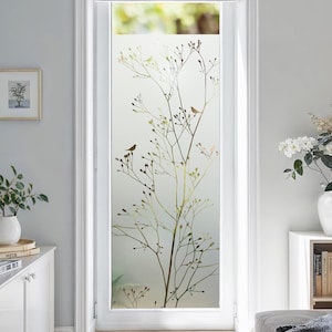 Könnte beinhalten: Eine Milchglasfensterscheibe mit einem von der Natur inspirierten Design. Das Design zeigt einen Baumzweig mit kleinen Vögeln. Die Farbpalette umfasst Braun-, Grün- und Weißtöne und erzeugt eine ruhige und natürliche Ästhetik. Das Fenster ist in einem weißen Türrahmen.