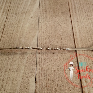 May include: A silver cocktail stirring spoon with a red plastic end and a twisted handle.