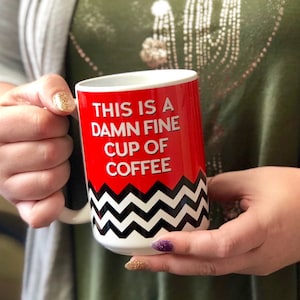 May include: White coffee mug with a red background and black and white chevron pattern. The mug says "This is a damn fine cup of coffee".