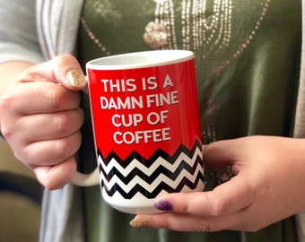 May include: White coffee mug with a red background and black and white chevron pattern. The mug says "This is a damn fine cup of coffee".