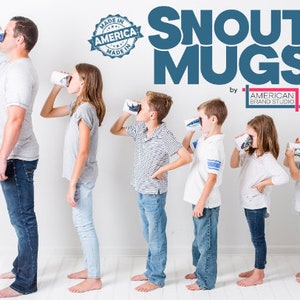May include: A group of people of different ages are drinking from blue and white ceramic mugs with a dog snout design. The mugs are labeled 'Snout Mugs' with the text 'by American Brand Studio' below. The text 'Made in America' is in a blue circle with a white star in the center. The mugs are part of a product line for dog lovers.