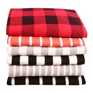 May include: A stack of folded fabric with various patterns. The top layer is red and black buffalo plaid. Below are layers with orange and white stripes, gray and white stripes, black and white stripes, and gray and white stripes.