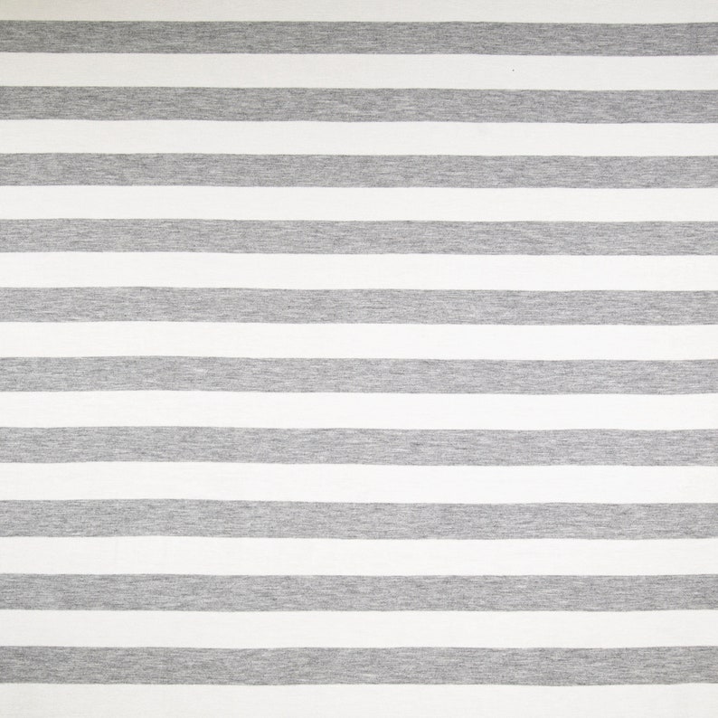 May include: A close-up shot of a fabric with a repeating pattern of horizontal stripes. The stripes alternate between wide bands of white and gray. The fabric appears to be a soft knit material, suitable for clothing or home decor.