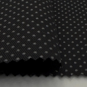 May include: Close-up of a black fabric with a repeating pattern of small, raised, gray dots. The fabric is folded, revealing a dark underside and a textured surface. The fabric has a woven appearance.