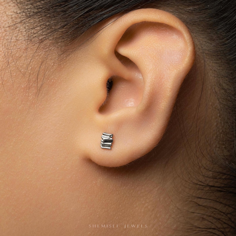 A close-up view of a person's ear, showing a small silver earring in the earlobe.