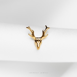 May include: A gold-colored deer head pendant with detailed antlers. The jewelry piece is set against a white background. The brand name "SHE MISLI JEWELS" is printed at the bottom.