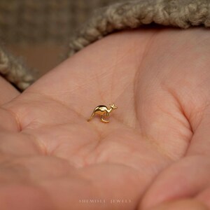 a person holding a tiny gold bird on their palm
