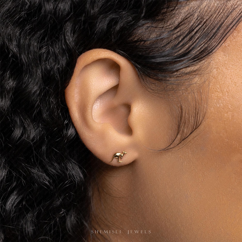 a close up of a person's ear wearing a gold earring