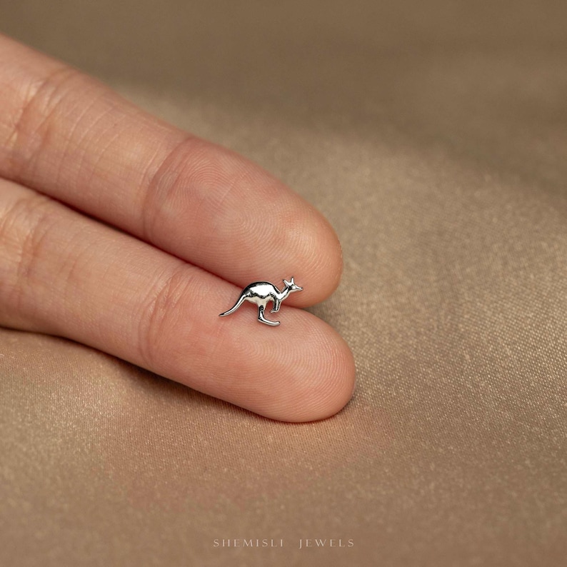 a person's hand holding a tiny silver bird ring