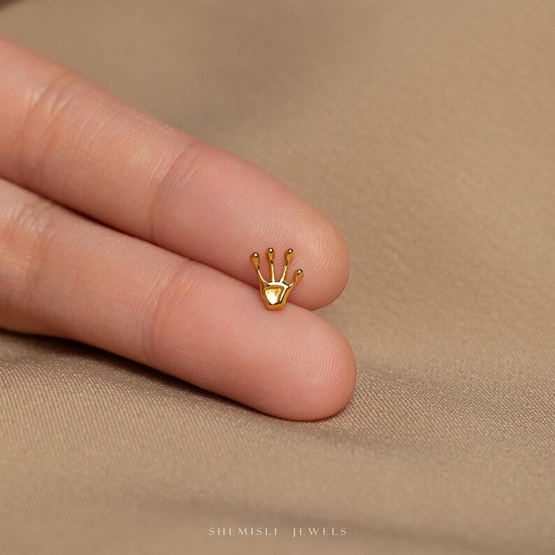 a person wearing a gold ring with a crown on it