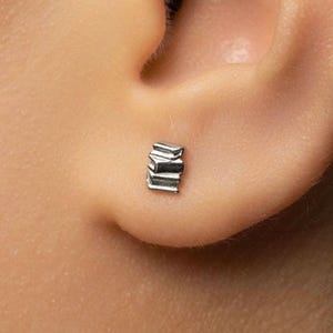 A close-up view of a person's ear, showing a small silver earring in the earlobe.
