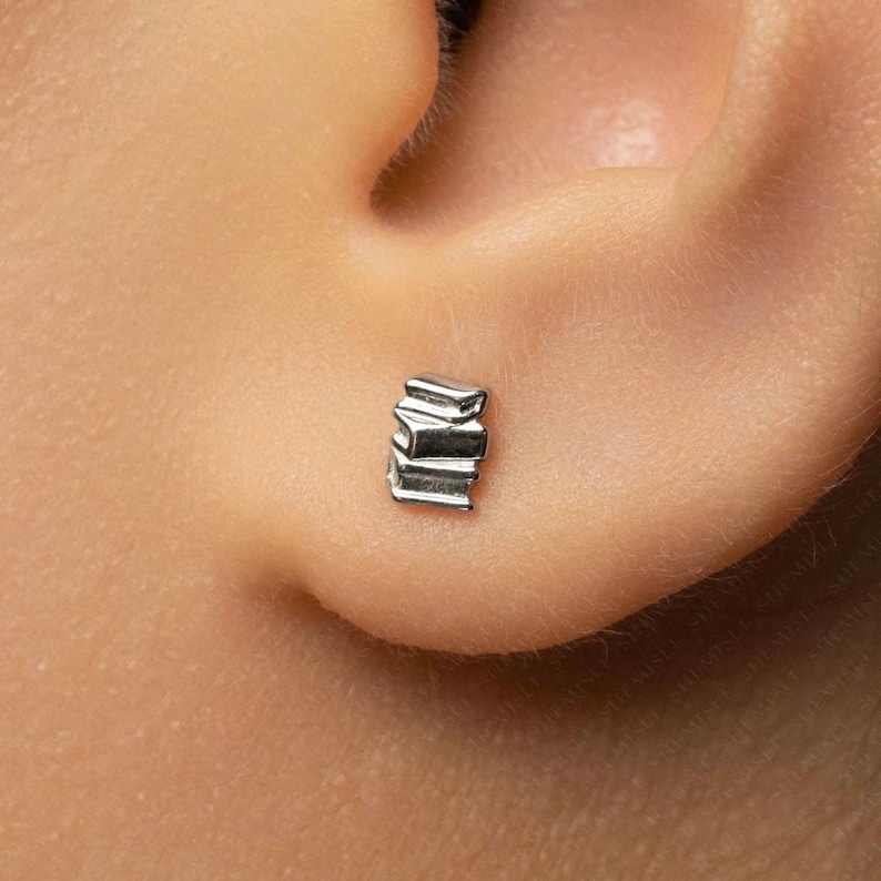 A close-up view of a person's ear, showing a small silver earring in the earlobe.
