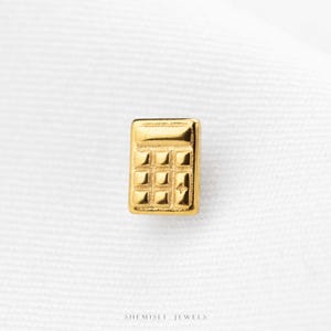 A small gold-colored calculator-shaped object is shown against a white background.