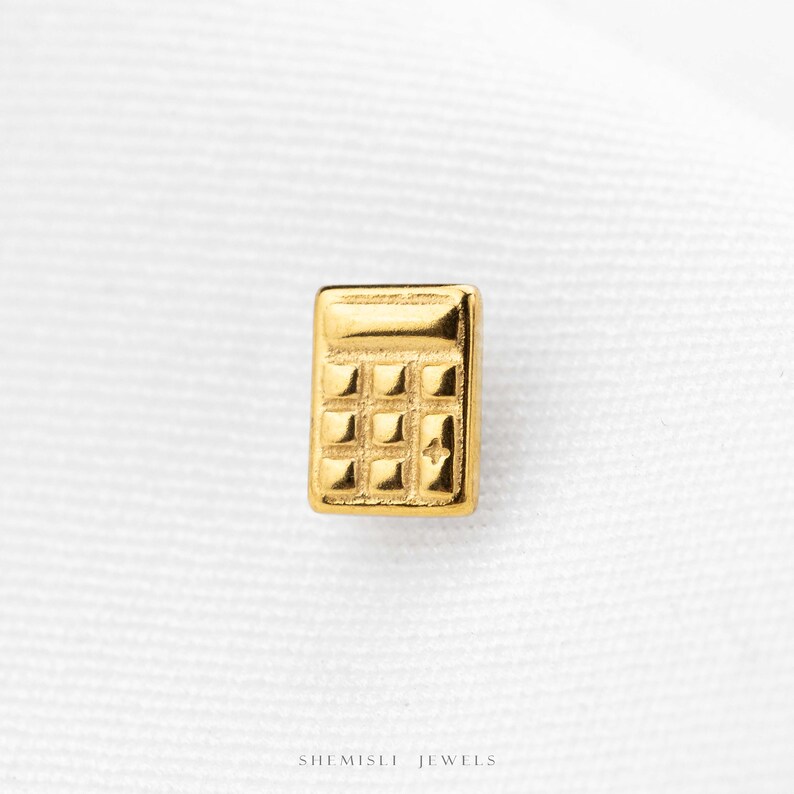 A small gold-colored calculator-shaped object is shown against a white background.