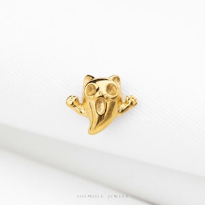 May include: A small gold-toned stud earring shaped like a ghost with raised arms, two circular eye cutouts, and an open mouth. The piece features a polished metallic finish and is positioned above the text SHEMISLI JEWELS at the bottom.