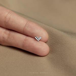 a person's left hand with a small diamond ring on it