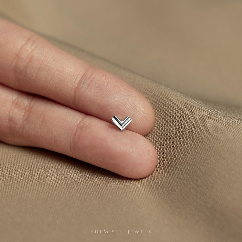 a person's left hand with a small diamond ring on it