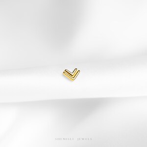 a close up of a white cloth with a small gold v on it
