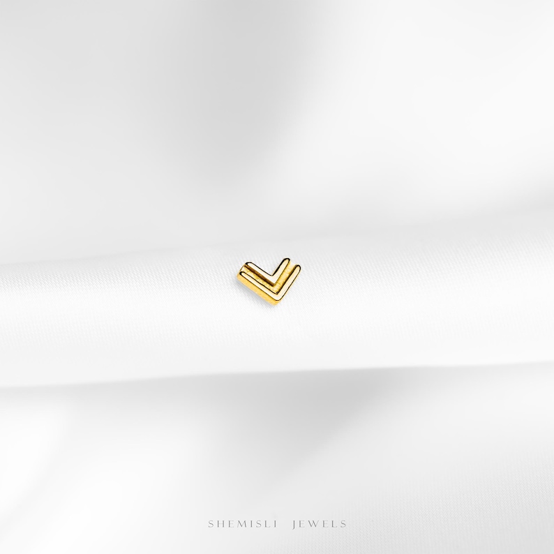a close up of a white cloth with a small gold v on it