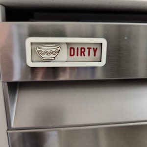 May include: A white magnetic sign with a red "DIRTY" label and a black and white icon of a bowl, indicating a dishwasher is dirty.