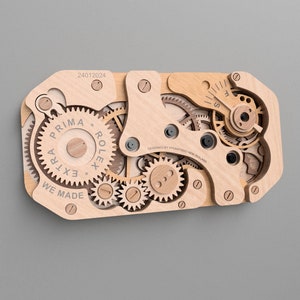May include: Wooden wall art depicting the inner workings of a watch, featuring gears, levers, and the text "PRIMA EXTRA ROLEX WE MADE". The design includes the text "24012024" and "DESIGNED BY VIVASTUDIO NEW ZEALAND".