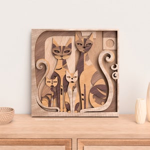 May include: Wooden wall art featuring a family of stylized cats. The artwork is crafted from layered wood in shades of brown and tan, creating a three-dimensional effect. The cats are depicted with geometric features and sit within a square frame.