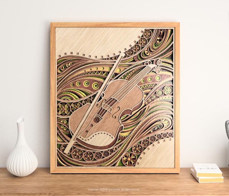 May include: Wooden framed artwork featuring a detailed violin and bow design. The layered wood art showcases a light brown violin with intricate cutouts, set against a backdrop of swirling patterns in shades of brown, green, and yellow. The frame is a light wood color.