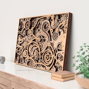 Puede incluir: Arte mural de madera con un diseño en capas de engranajes y componentes mecánicos. La obra de arte tiene un acabado de madera natural con un marco marrón oscuro. El intrincado diseño crea un efecto tridimensional.