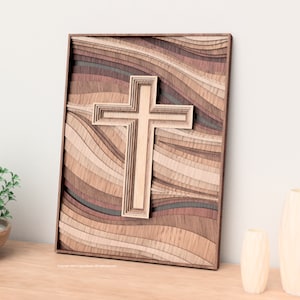 Puede incluir: Una obra de arte de cruz de madera en capas. La cruz es de color marr&oacute;n claro y es el punto focal, sobre un fondo de madera ondulada y en capas en tonos marrones y beige. La obra est&aacute; enmarcada en madera marr&oacute;n oscuro.