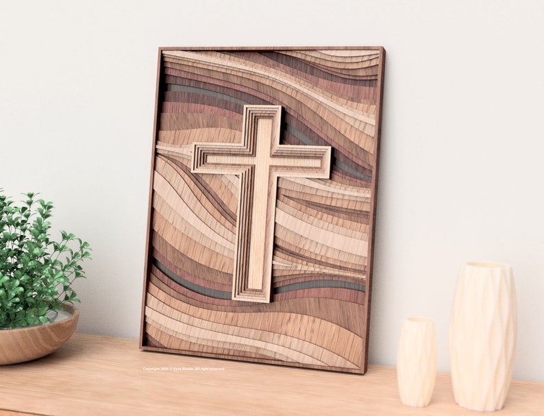 Puede incluir: Una obra de arte de cruz de madera en capas. La cruz es de color marr&oacute;n claro y es el punto focal, sobre un fondo de madera ondulada y en capas en tonos marrones y beige. La obra est&aacute; enmarcada en madera marr&oacute;n oscuro.