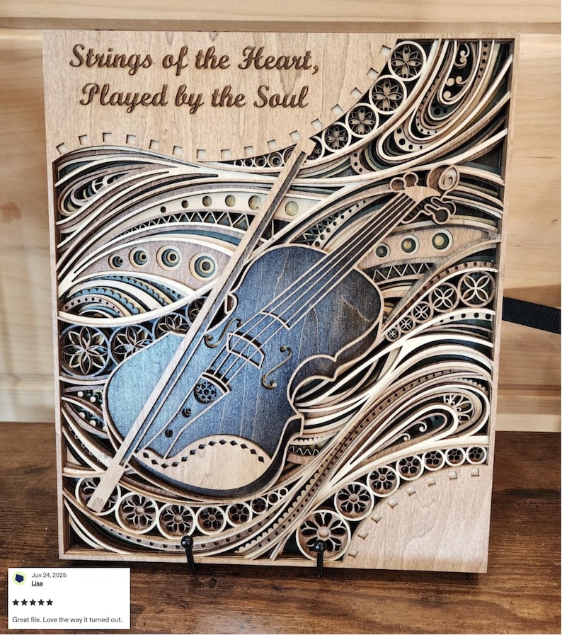 May include: A wooden layered art piece featuring a violin with a bow, set against a backdrop of swirling, decorative patterns. The text "Strings of the Heart, Played by the Soul" is at the top. The artwork is primarily in shades of brown and blue.
