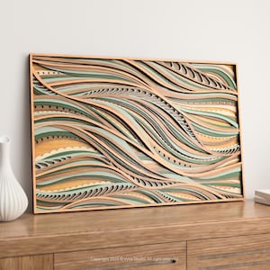 May include: A layered wooden wall art piece with a wave-like design. The artwork features shades of green, tan, and peach, creating a textured, three-dimensional effect. The piece is framed in natural wood and rests on a wooden surface.