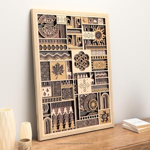 May include: A wooden wall art piece with a light wood frame. The artwork features a layered design with various shapes and patterns, including a sun, maple leaf, and trees. The artwork is displayed on a wooden surface.